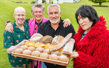 Hosts Noel Fielding and Matt Lucas stand with judges Paul Hollywood and Prue Leith around a tray of baked goods outside the Bake Off Tent.