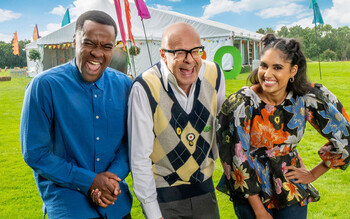 Liam Charles, Harry Hill and Ravneet Gill laughing in front of the Junior Bake Off tent