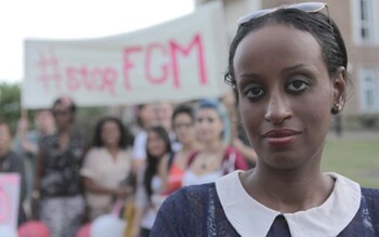 Leyla Hussein stands with campaigners in front of a '#STOP FGM' banner.