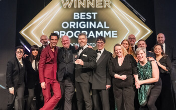 The Love Productions team stand in a line on stage after receiving the award